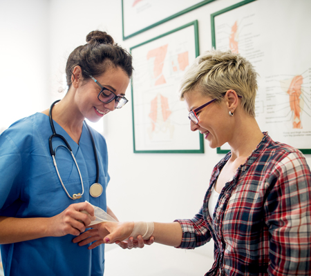 Image of nurse wrapping the arm of a patient after a surgery